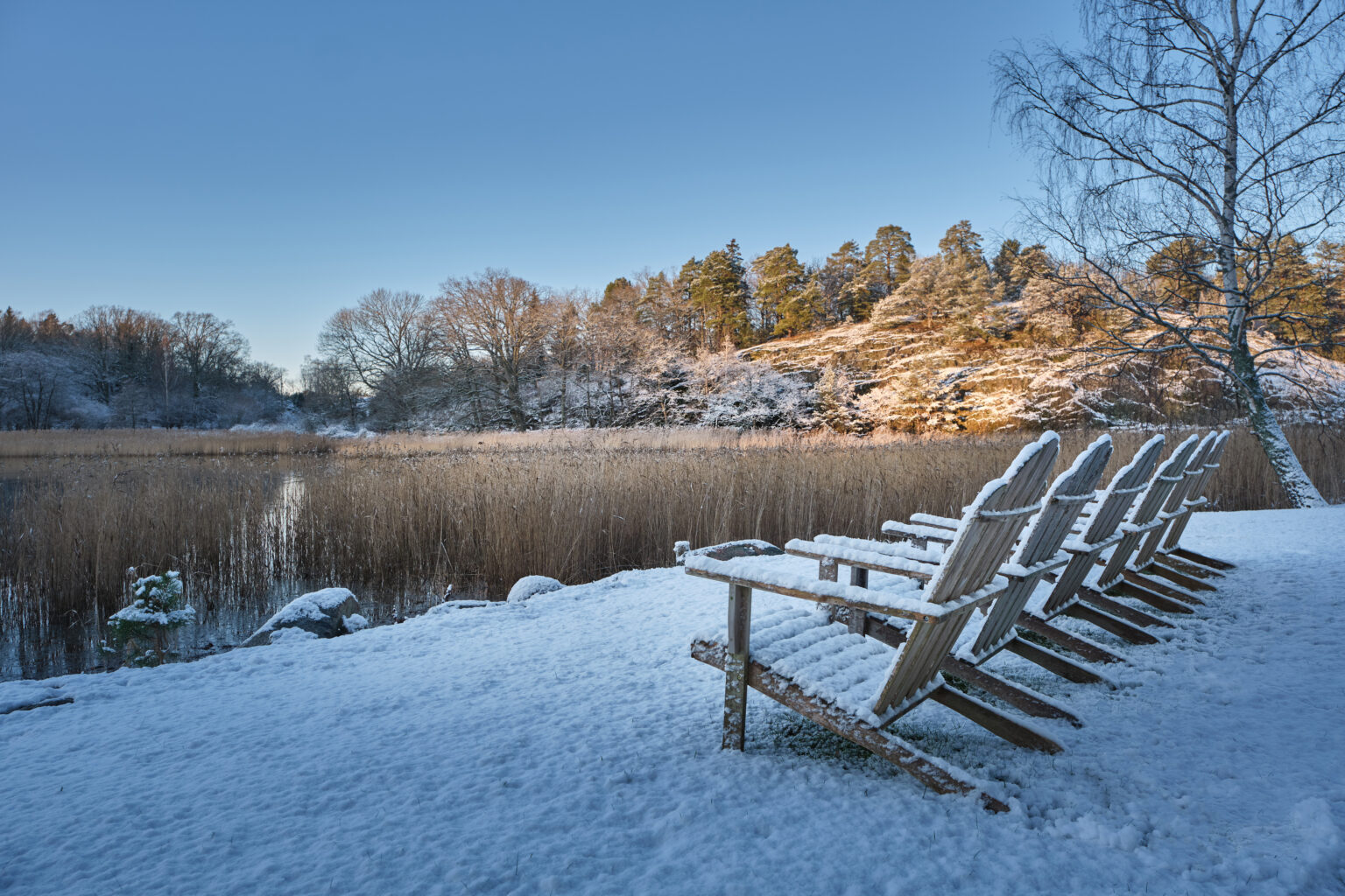 Stolar på bryggan vid vattnet på Villa Sandudden