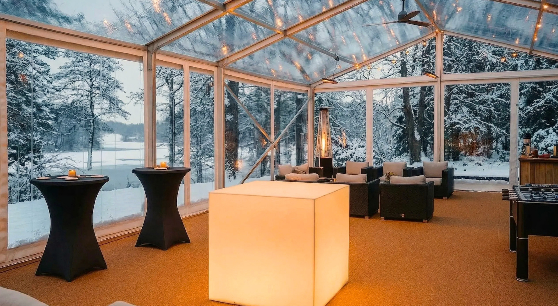 Glasat tält med levande ljus och loungemöbler i snölandskap vid havet på Villa Sandudden